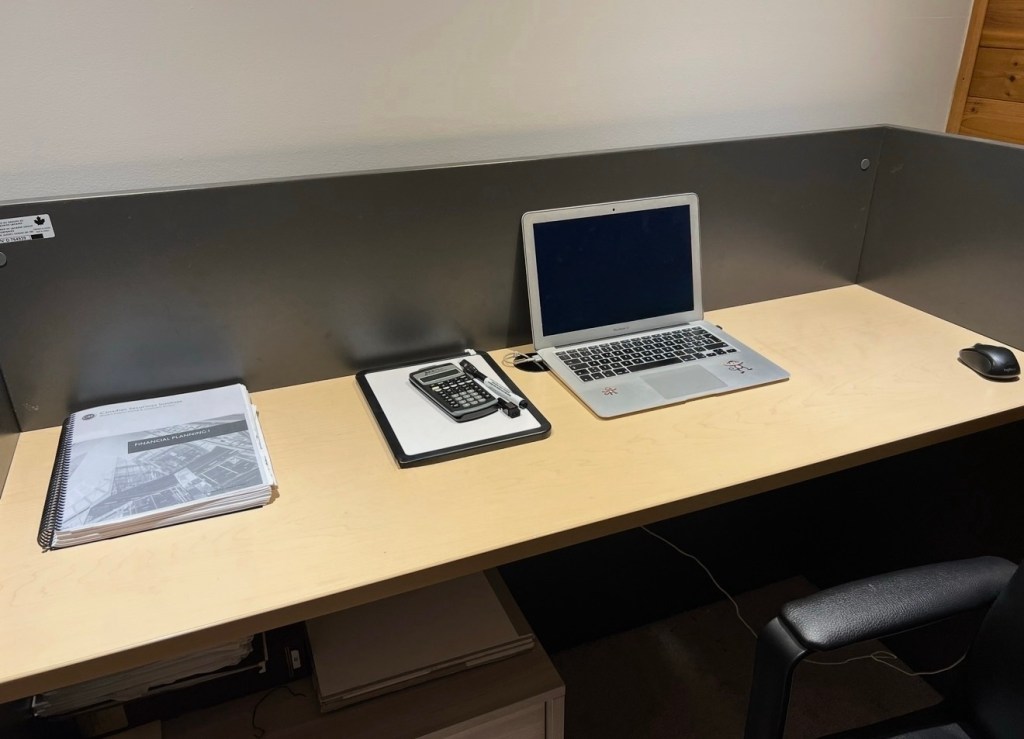 Student studying in Canada with laptop, notes and calculator